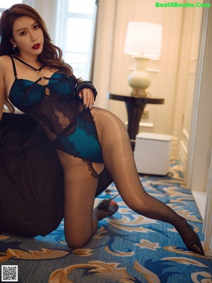 A woman in a black jacket and blue lingerie posing for the camera.