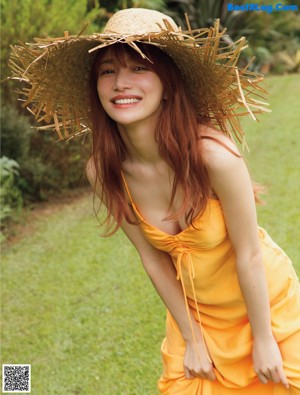 A woman in a straw hat is posing for a picture.