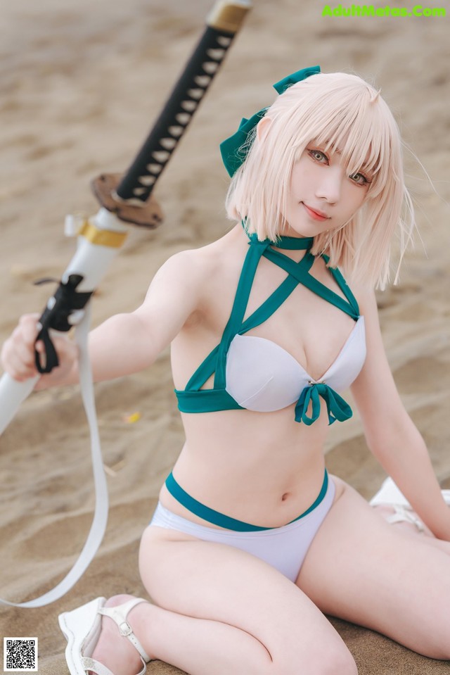 A woman in a bikini holding a sword on the beach.