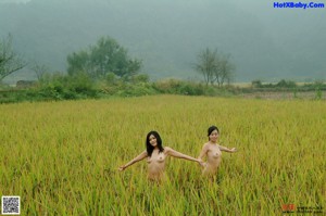 A naked woman sitting on a wooden bench in the woods.