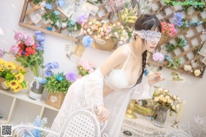 A woman in a white lingerie sitting on the floor.