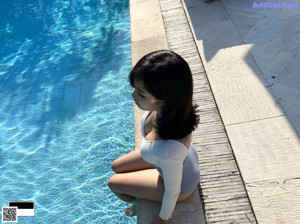 A woman in a white bathing suit standing next to a hot tub.