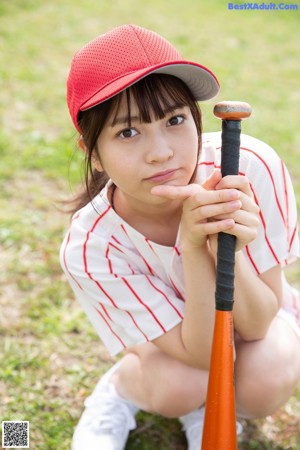 A woman in a baseball uniform holding a baseball bat.