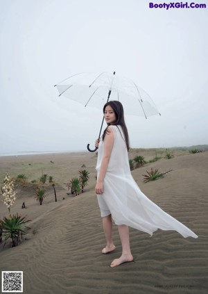 A woman sitting on the ground in front of a white wall.