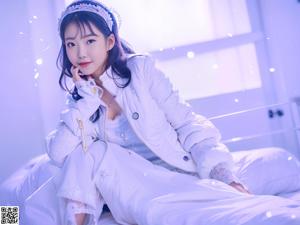 A woman in a white lingerie sitting on a bed.