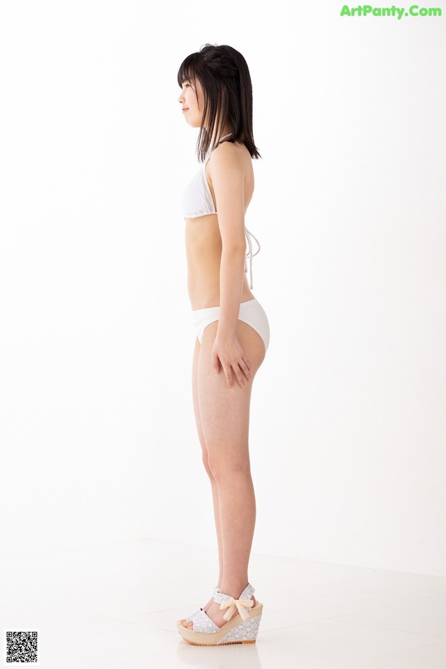 A woman in a white bikini standing on a white floor.