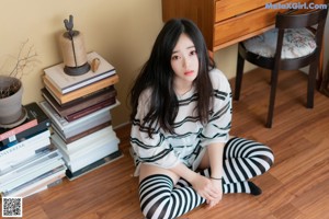 A woman sitting on a bed in a bedroom.