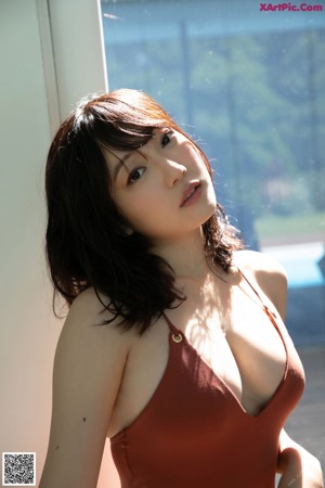 A woman in a red bathing suit leaning against a window.