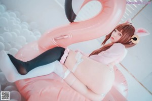 A woman in a pink outfit is posing in a pool of balloons.