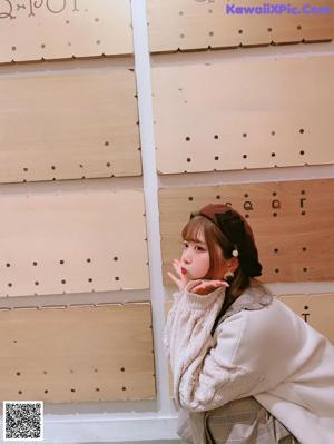 A young girl wearing a white coat and a brown hat.