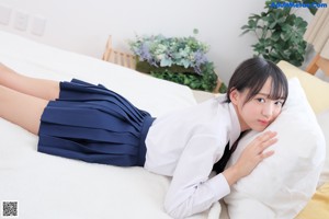 A woman in a white shirt and tie laying on a bed.