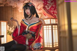 A woman in a red and black kimono sitting on the floor.