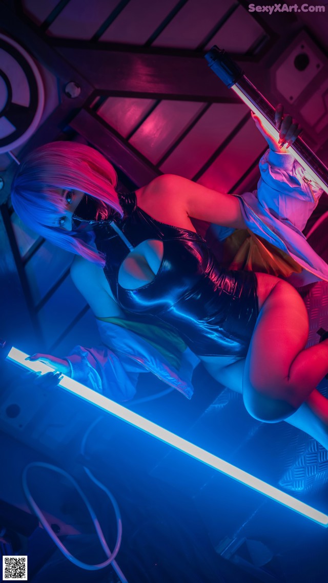 A woman in a latex outfit holding a light saber.