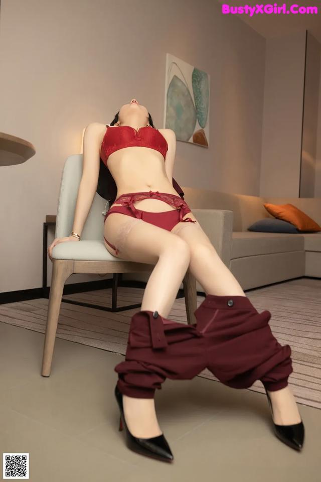 A woman in a red lingerie sitting on a chair.