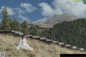 A woman in a white dress holding an umbrella on top of a mountain.