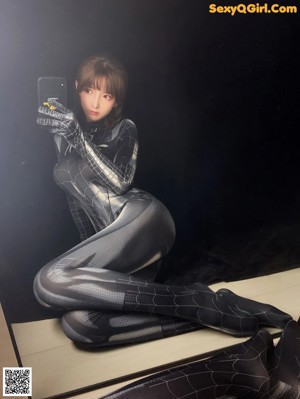 A woman in a black and silver spider suit posing for a picture.