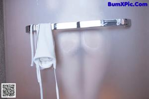 A woman in a white bikini standing in front of a mirror.