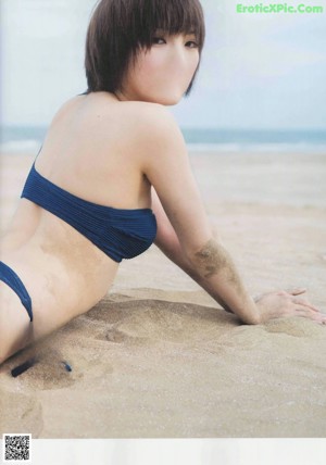 A woman in a blue bikini laying on the beach.