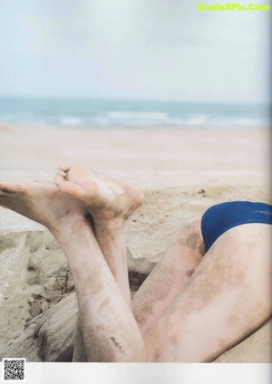 A woman in a blue bikini sitting on the ground.