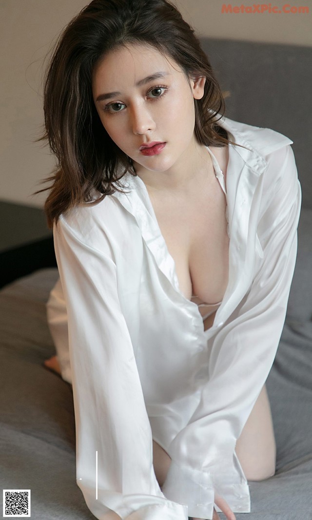 a woman in a white shirt sitting on a bed