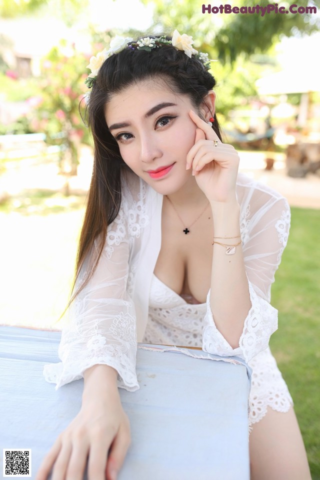 A woman in a white dress sitting on a bench.