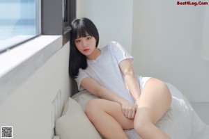 A woman laying on a bed wearing a white shirt and panties.