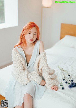 A woman with long red hair laying on a bed.